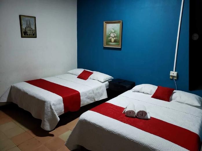 Habitación con dos camas matrimoniales y pared azul