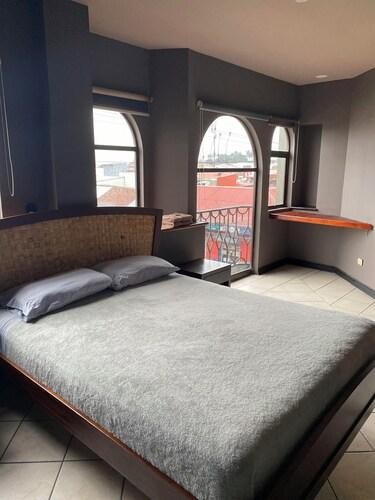 Privada con cama king y ventanales de arco con balcón