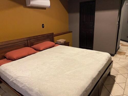 Privada con cama matrimonial, pared amarilla y aire acondicionado