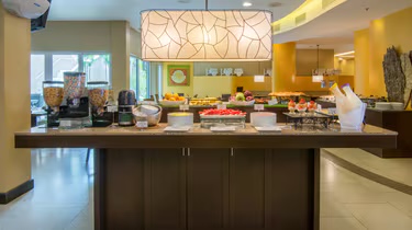 Barra de desayuno buffet con fruta, cereales y máquina de café