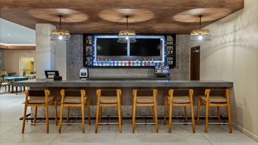 Barra con taquetes de madera, dispensador de bebidas y cielo raso de listones