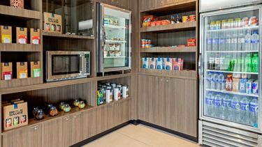 Tienda de conveniencia con estantes de snacks, refrigerador de bebidas y microondas