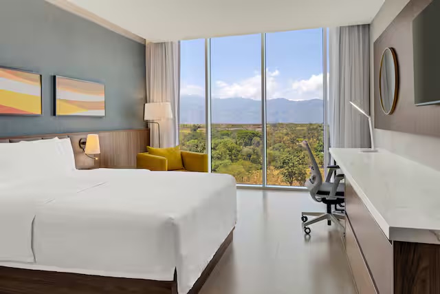 Habitación con cama king, escritorio y ventanal de piso a techo con vista a las montañas