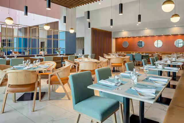 Restaurante con mesas montadas, lámparas colgantes y pared de listones de madera