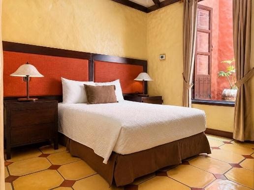 Habitación con cama matrimonial, pared terracota y ventanal al patio