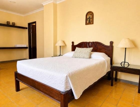Habitación con piso de barro y cama matrimonial