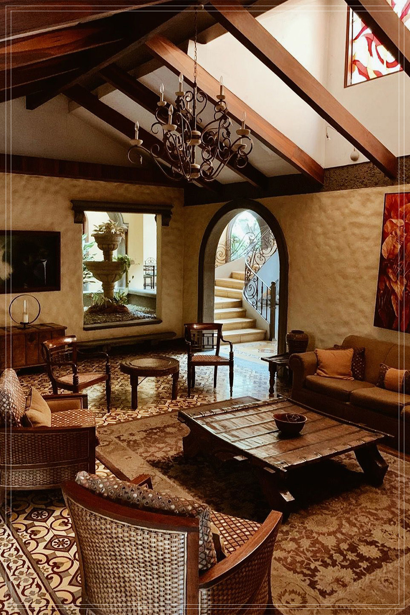 Sala colonial con candelabro de hierro, fuente al fondo y piso de mosaico