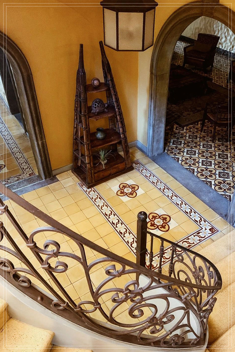 Escalera de caracol vista desde arriba, sobre piso de mosaico ornamentado