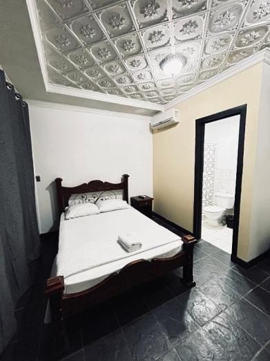 Habitación con cama matrimonial, baño privado y cielo raso decorado
